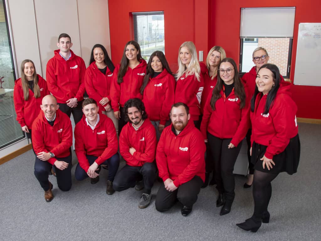 The Europa Road Team in Sheffield smile together in red, Europa branded hoodies