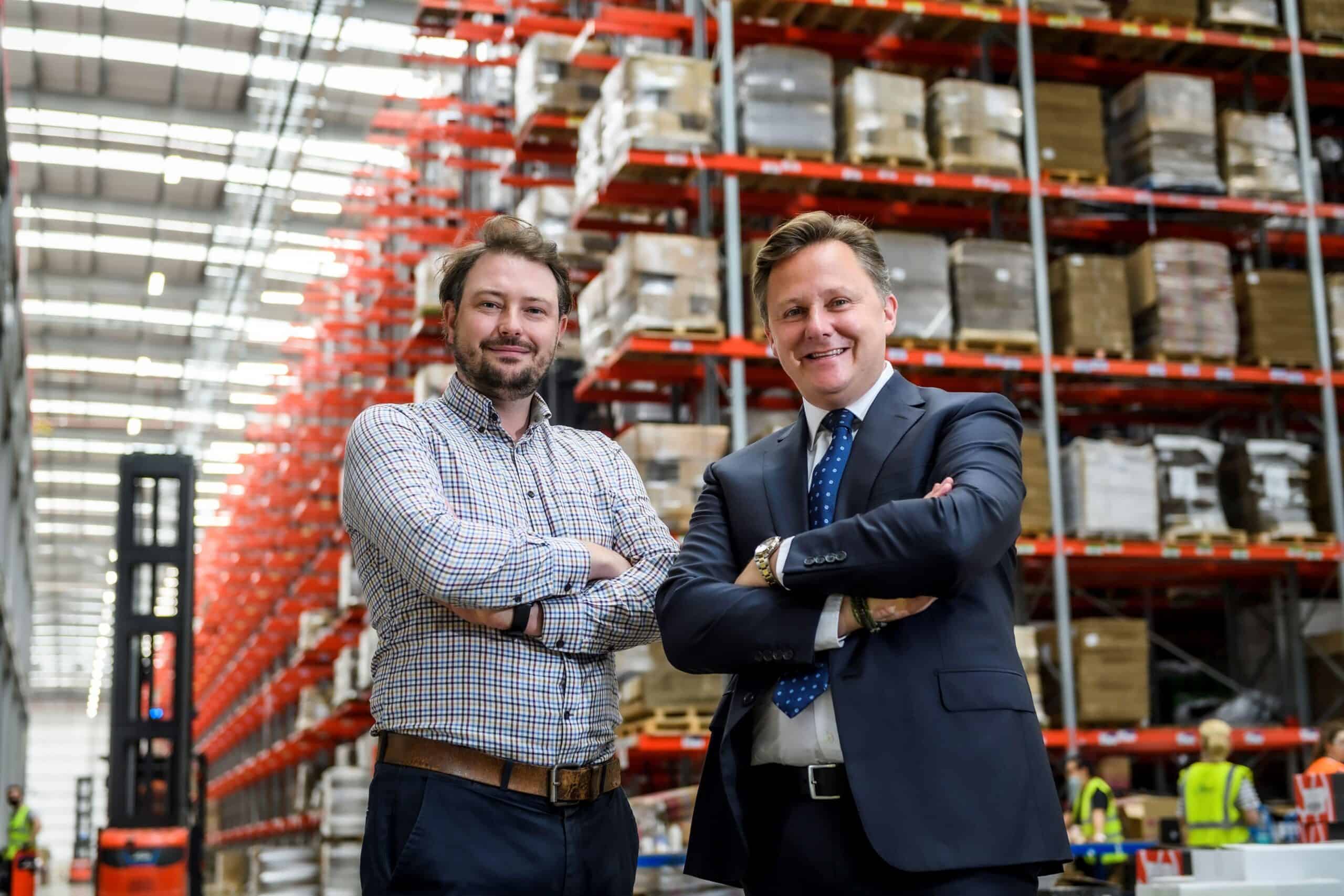 Tom Jenkins and Andrew Baxter stand side by side in a Europa Warehouse.