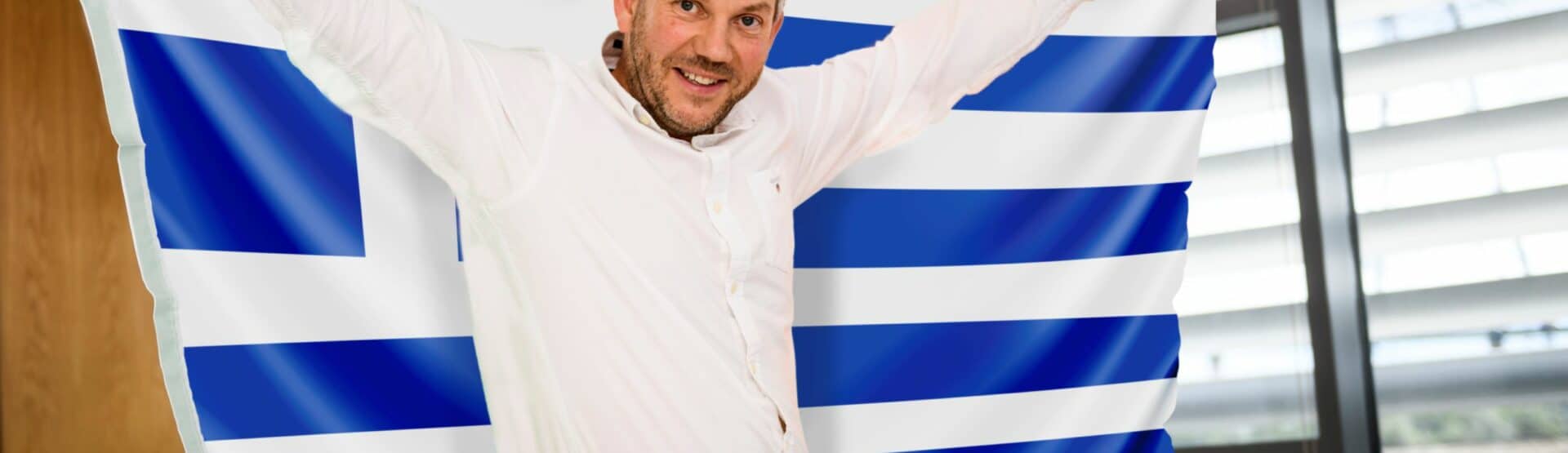 Dan Cook, Operations Director at Europa Worldwide Group, holding a Greek flag.